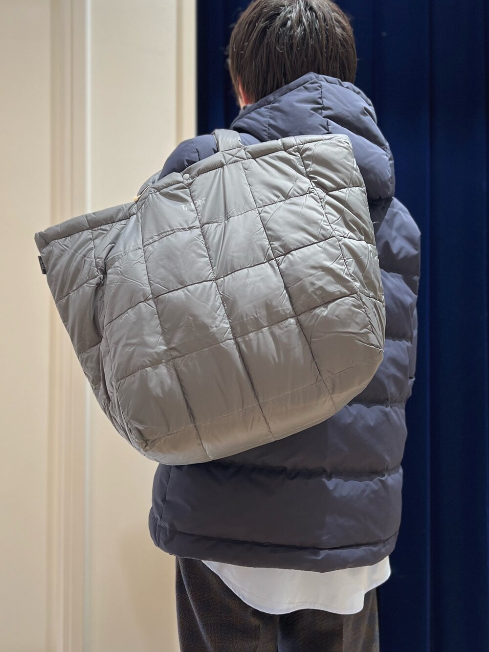 ブルー系のダウンジャケット/コート、ブルー系のシャツ/ブラウス、グレー系のトートバッグを着用したメンズの冬コーディネートの7枚目の写真