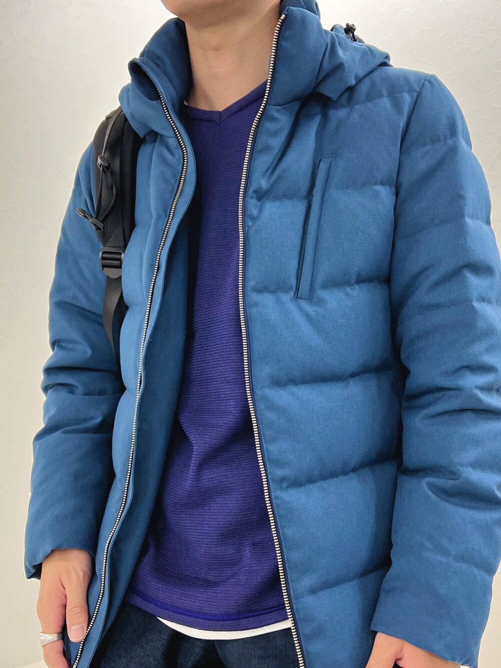 パープル系のニット/セーター、ブルー系のダウンジャケット/コート、ブラック系のバックパック/リュックを着用したメンズの秋コーディネートの6枚目の写真