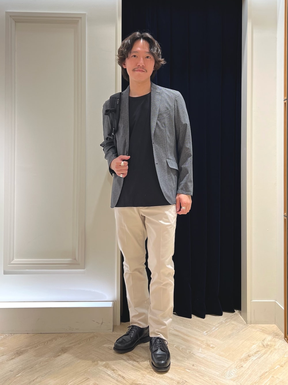 グレー系のテーラードジャケット、ブラック系のTシャツ/カットソー、ホワイト系のチノパンツを着用したメンズの春コーディネートの2枚目の写真