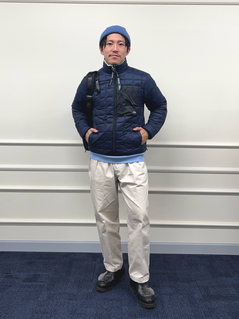 ブルー系のニット/セーター、ホワイト系のブルゾン、ブラック系のバックパック/リュックを着用したメンズの秋コーディネートの4枚目の写真