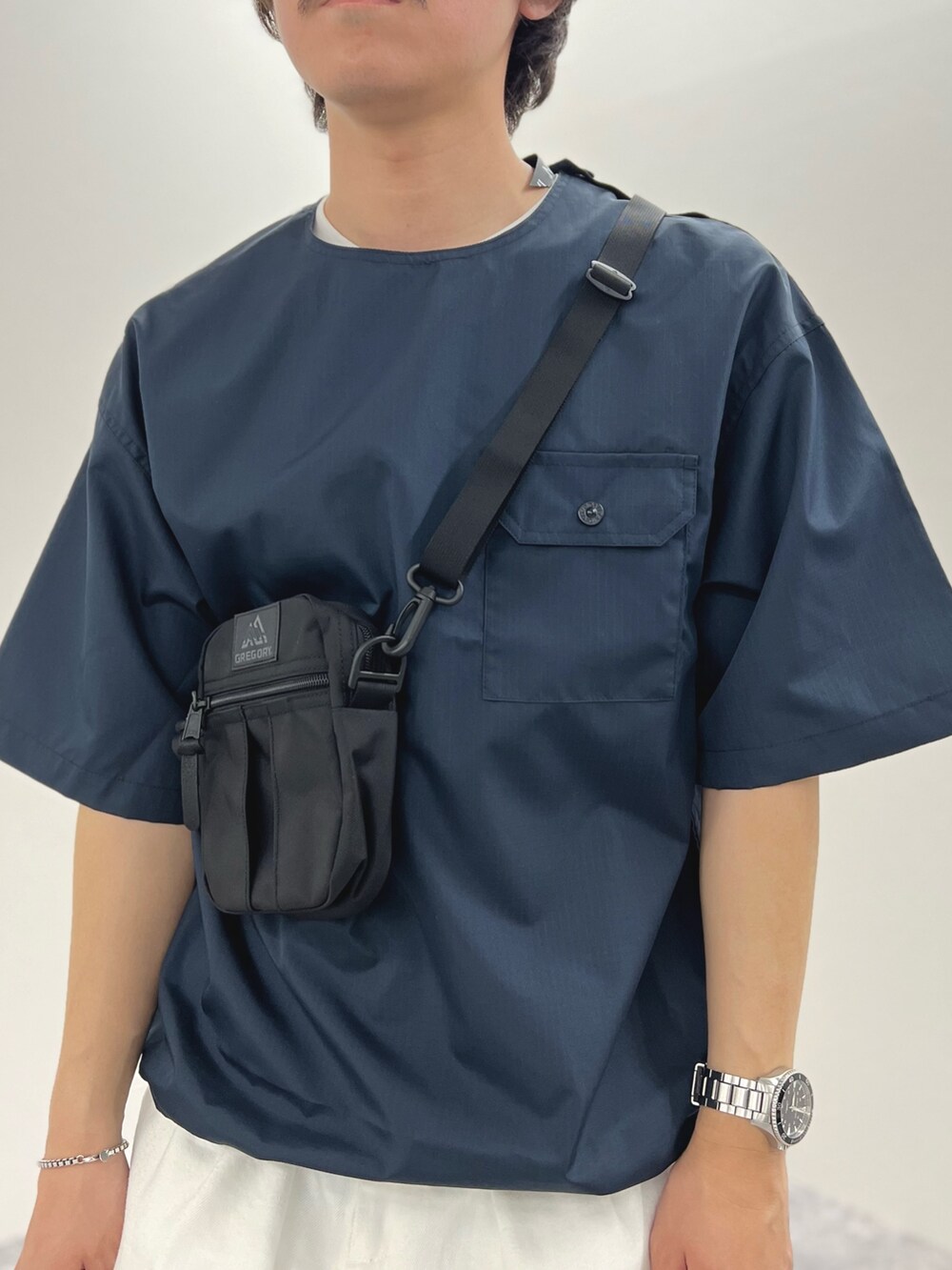 ブルー系のTシャツ/カットソー、ブラック系のショルダーバッグ、ホワイト系のデニムパンツを着用したメンズの春コーディネートの5枚目の写真