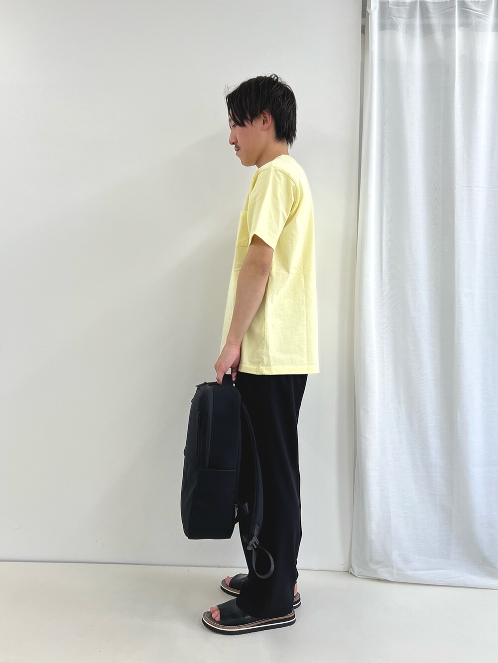 イエロー系のTシャツ/カットソー、ブルー系のその他パンツ、ブラック系のバックパック/リュックを着用したメンズの春コーディネートの4枚目の写真