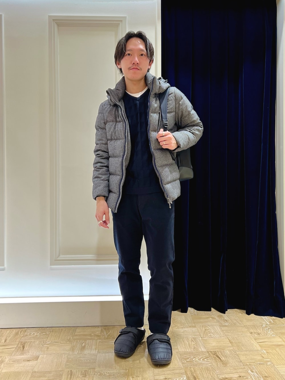 グレー系のダウンジャケット/コート、ブルー系のニット/セーター、ブラック系のバックパック/リュックを着用したメンズの冬コーディネートの3枚目の写真