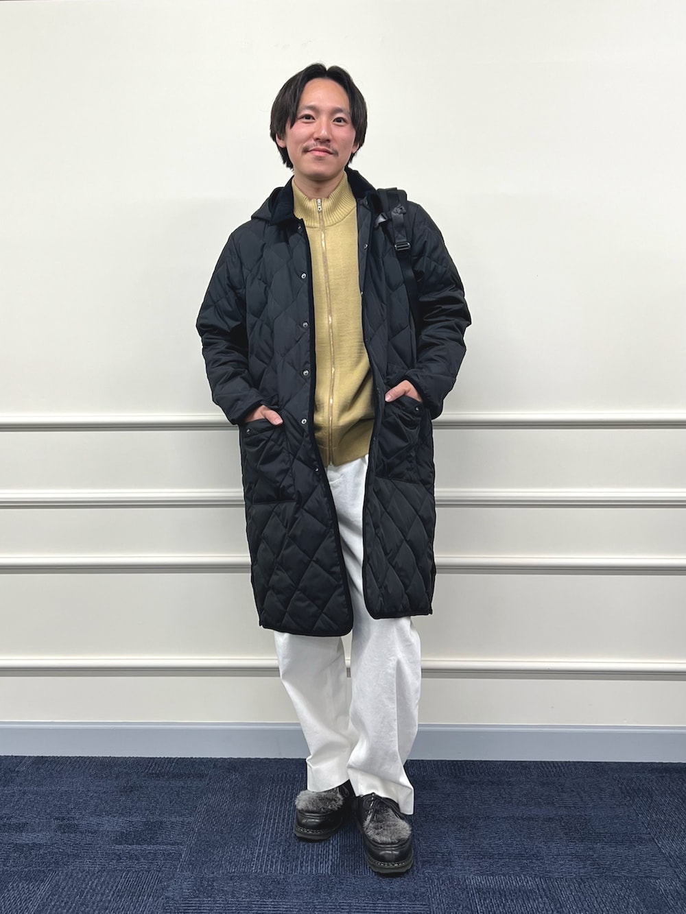 ブラック系のダウンジャケット/コート、ブラック系のバックパック/リュック、ベージュ系のカーディガン/ボレロを着用したメンズの冬コーディネートの5枚目の写真