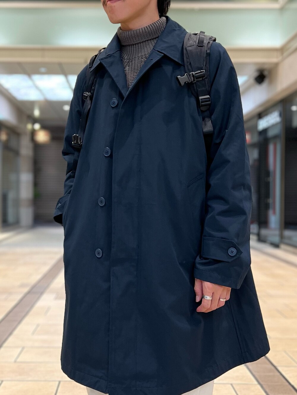 ブラック系のバックパック/リュック、ブルー系のステンカラーコート、ブラック系のシューズを着用したメンズの秋コーディネートの5枚目の写真