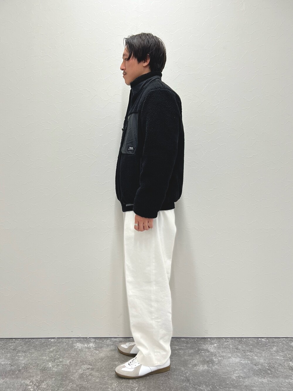 ブラック系のニット/セーター、ホワイト系のデニムパンツ、ブラック系のブルゾンを着用したメンズの冬コーディネートの4枚目の写真