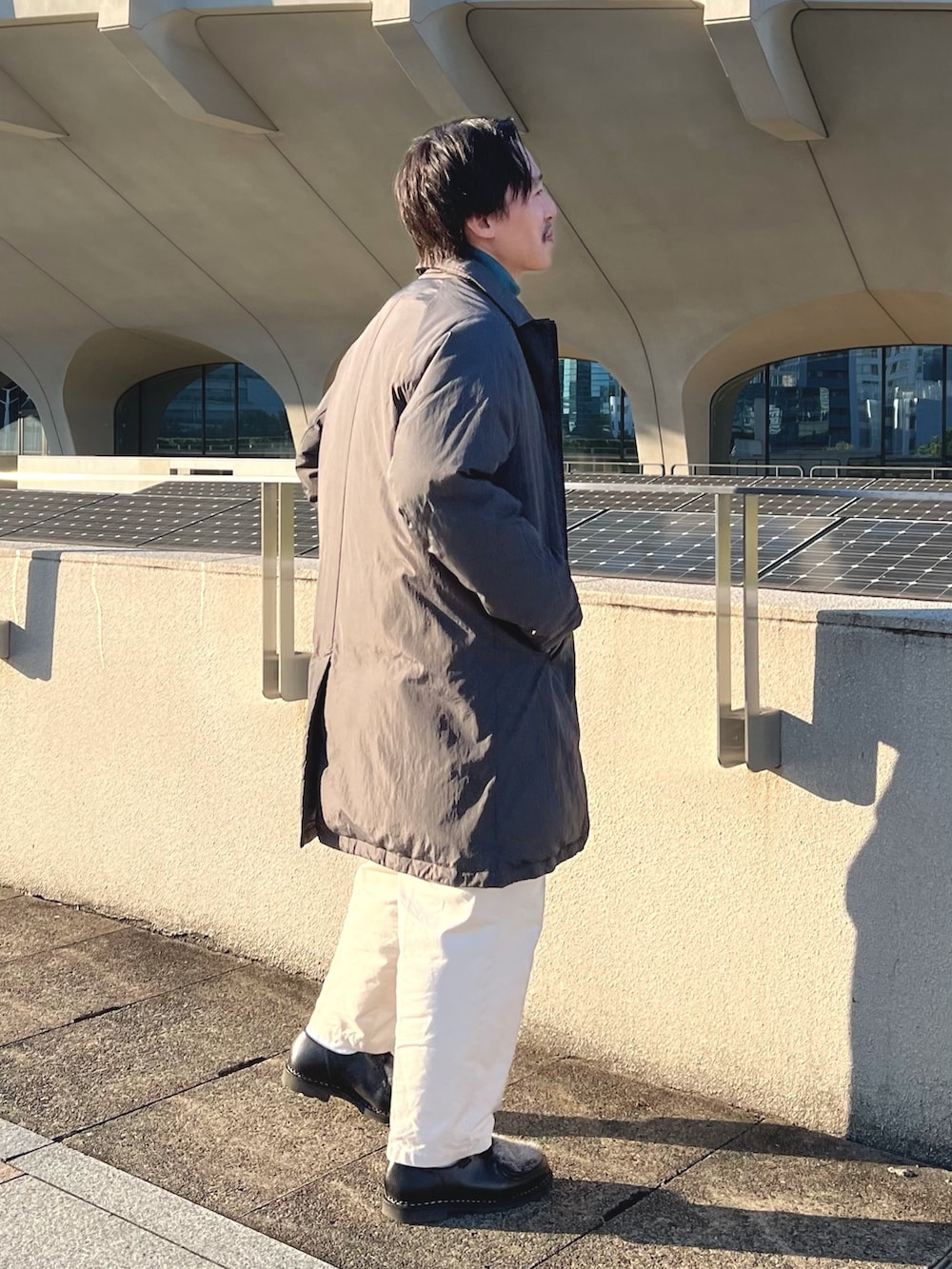 グレー系のダウンジャケット/コート、ブルー系のニット/セーター、ブラック系のその他シューズを着用したメンズの秋コーディネートの6枚目の写真