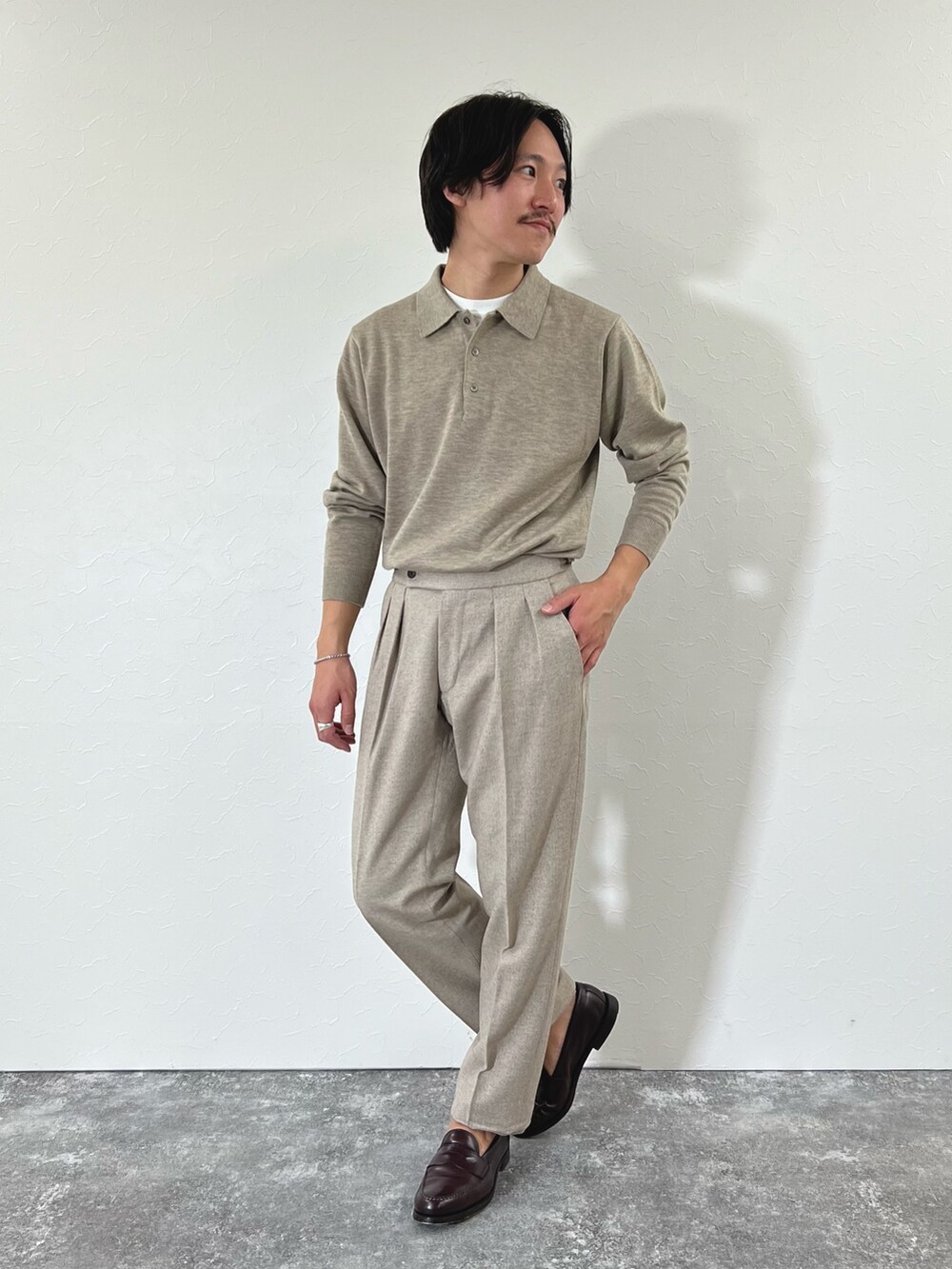ベージュ系のスラックス、ブラウン系のローファー、ベージュ系のニット/セーターを着用したメンズの冬コーディネートの3枚目の写真