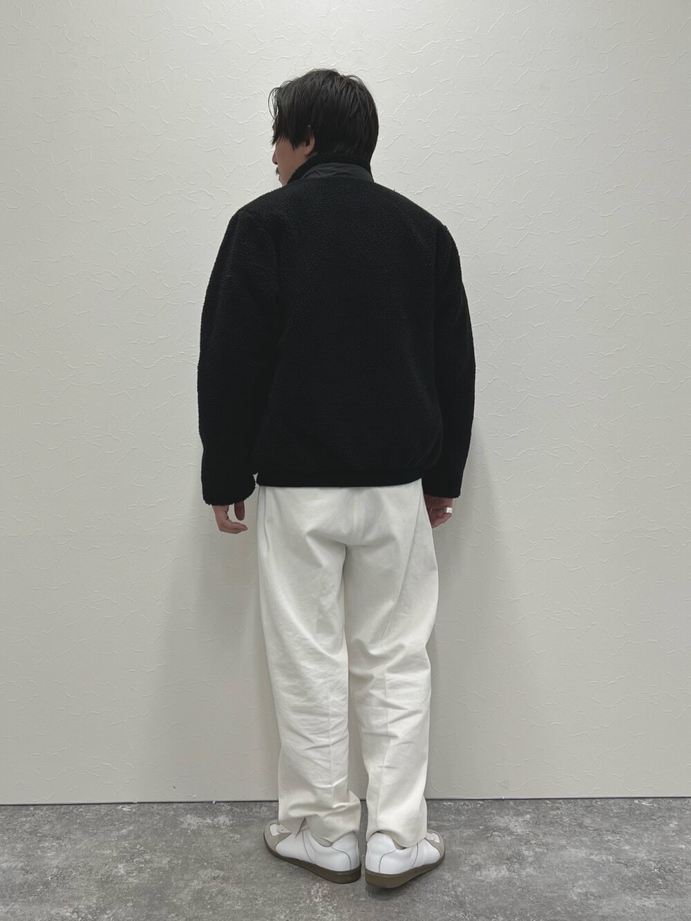 ブラック系のニット/セーター、ホワイト系のデニムパンツ、ブラック系のブルゾンを着用したメンズの冬コーディネートの5枚目の写真