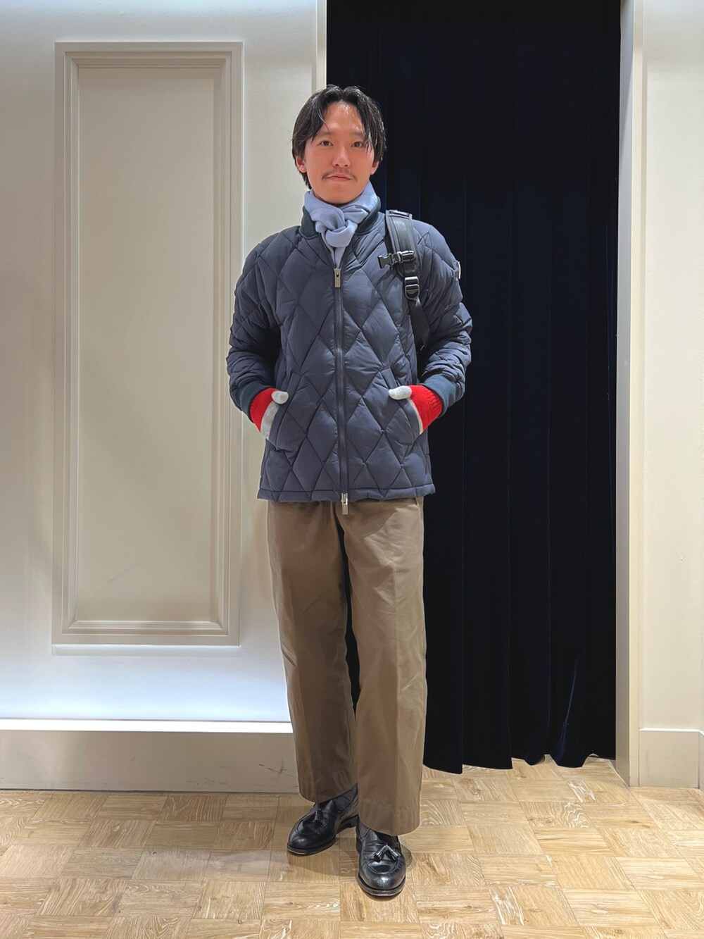 ブルー系のダウンジャケット/コート、ブラック系のバックパック/リュック、ブルー系のマフラーを着用したメンズの冬コーディネートの3枚目の写真