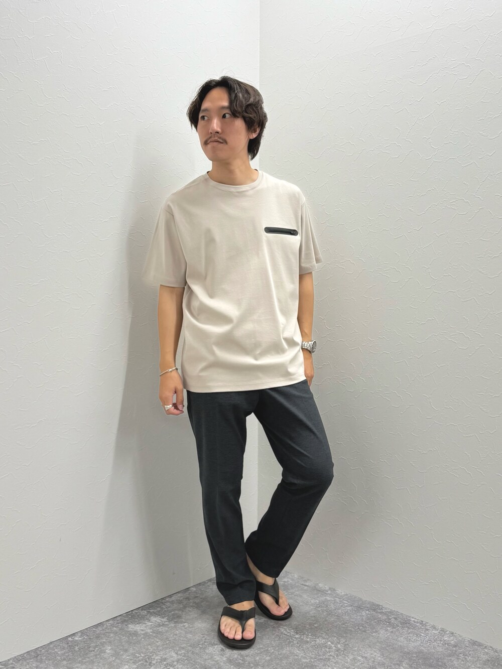 ベージュ系のTシャツ/カットソー、グレー系のその他パンツ、ブラック系のサンダルを着用したメンズの夏コーディネートの2枚目の写真