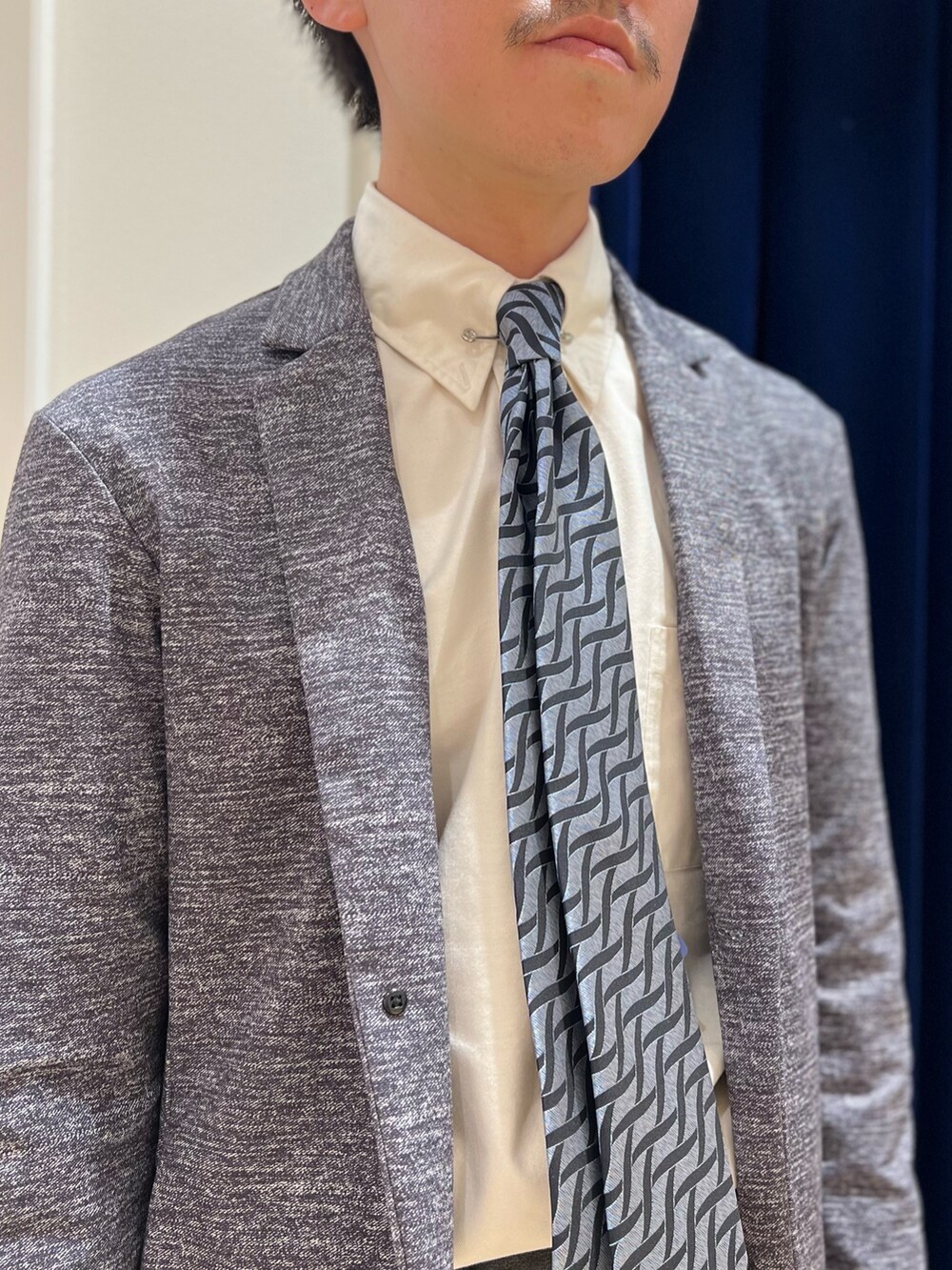 グレー系のカーディガン/ボレロ、ブルー系のネクタイ、ブラック系のトートバッグを着用したメンズの冬コーディネートの5枚目の写真