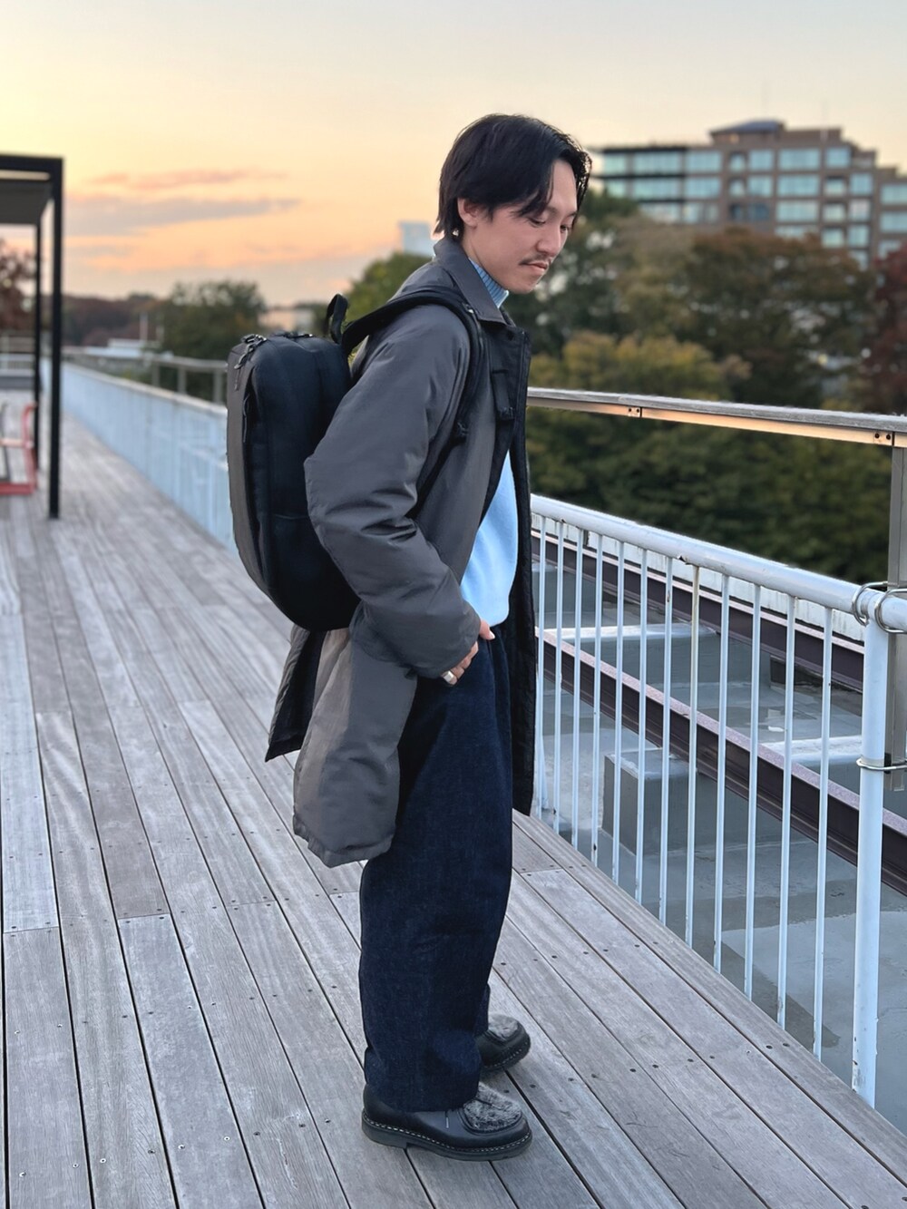 グレー系のダウンジャケット/コート、ブルー系のニット/セーター、ブラック系のバックパック/リュックを着用したメンズの冬コーディネートの4枚目の写真