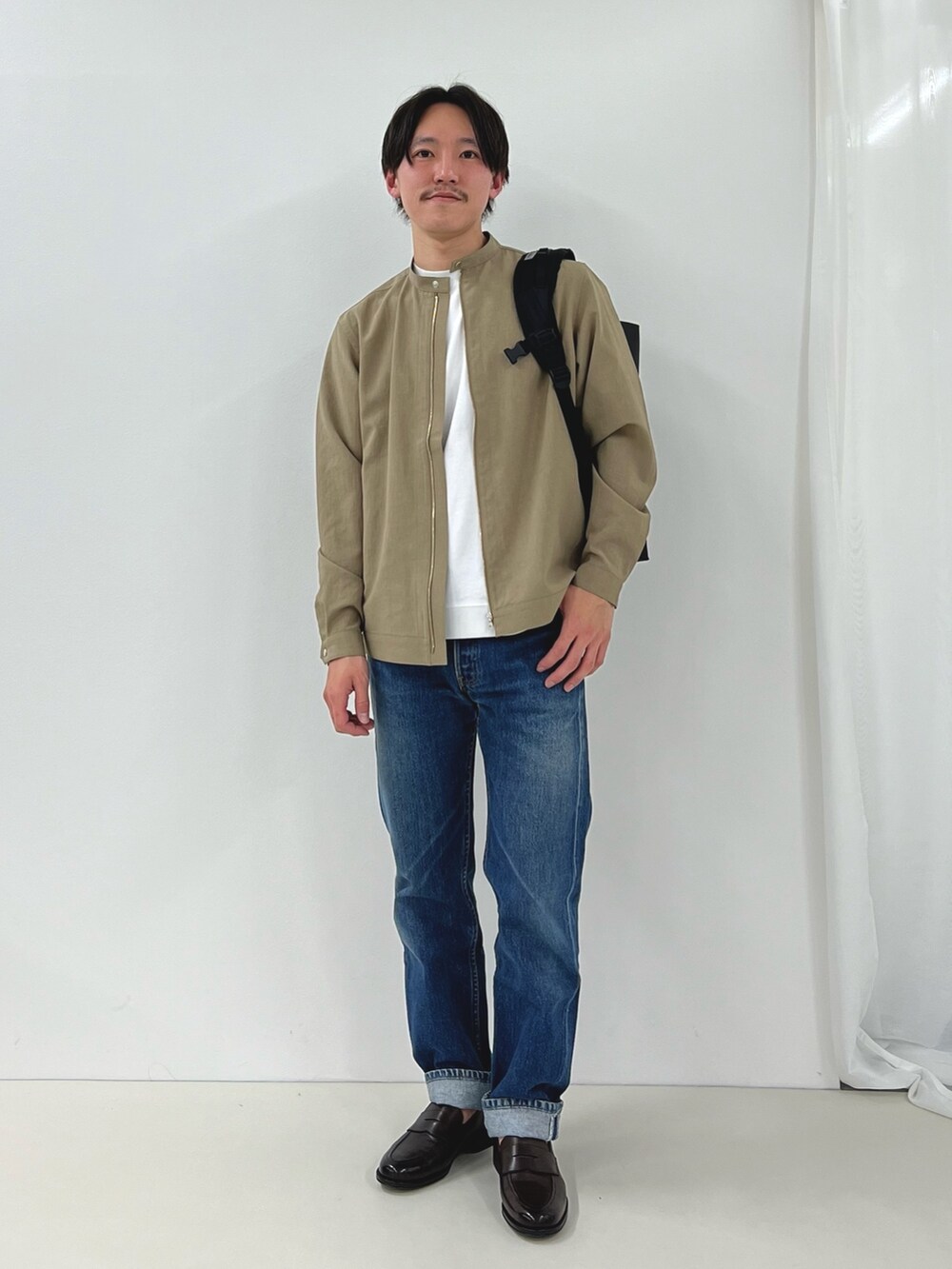 ホワイト系のTシャツ/カットソー、ベージュ系のブルゾン、ブラック系のバックパック/リュックを着用したメンズの春コーディネートの2枚目の写真