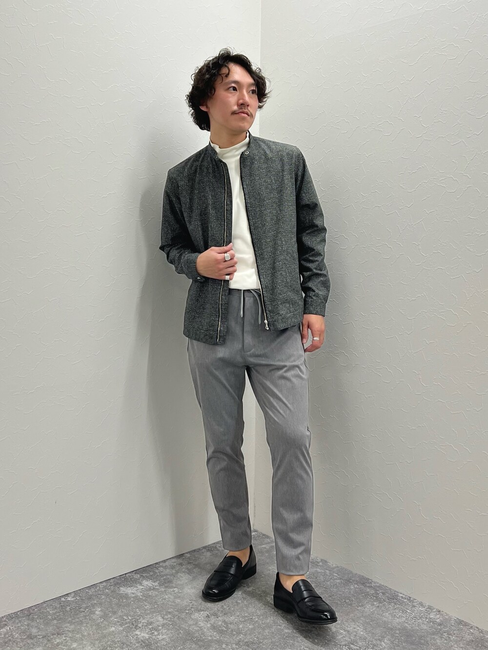 グレー系のブルゾン、ホワイト系のTシャツ/カットソー、グレー系のチノパンツを着用したメンズの冬コーディネートの2枚目の写真