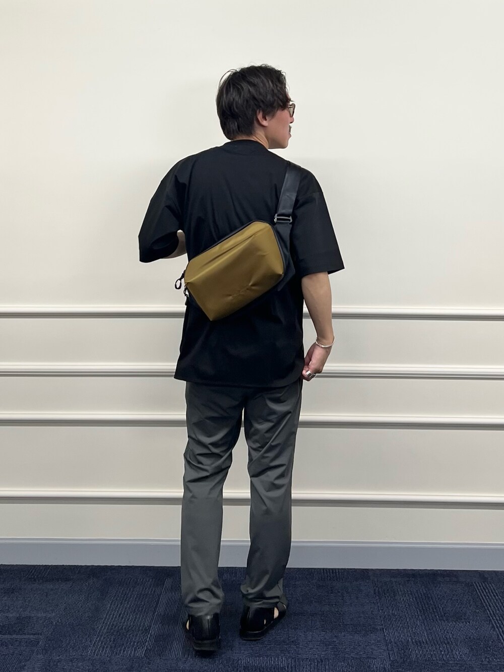 ブラック系のTシャツ/カットソー、グリーン系のショルダーバッグ、グレー系のその他パンツを着用したメンズの春コーディネートの6枚目の写真