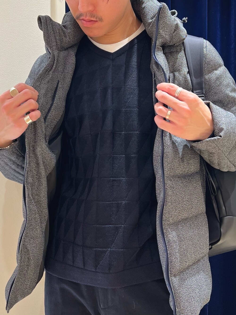 グレー系のダウンジャケット/コート、ブルー系のニット/セーター、ブラック系のバックパック/リュックを着用したメンズの冬コーディネートの6枚目の写真