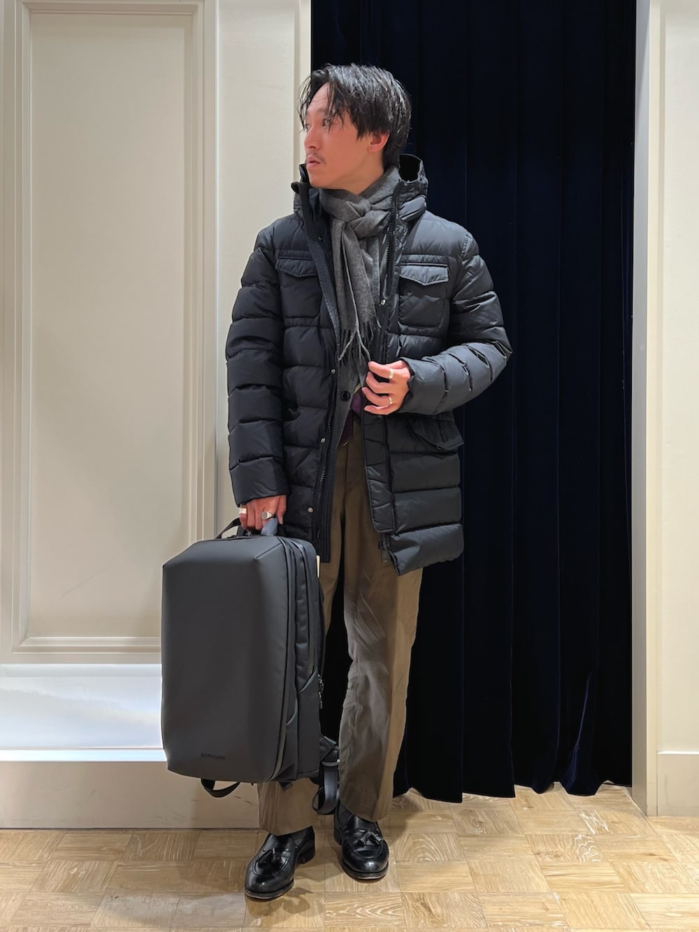 グレー系のテーラードジャケット、ブラック系のバックパック/リュック、ブラック系のダウンジャケット/コートを着用したメンズの冬コーディネートの3枚目の写真
