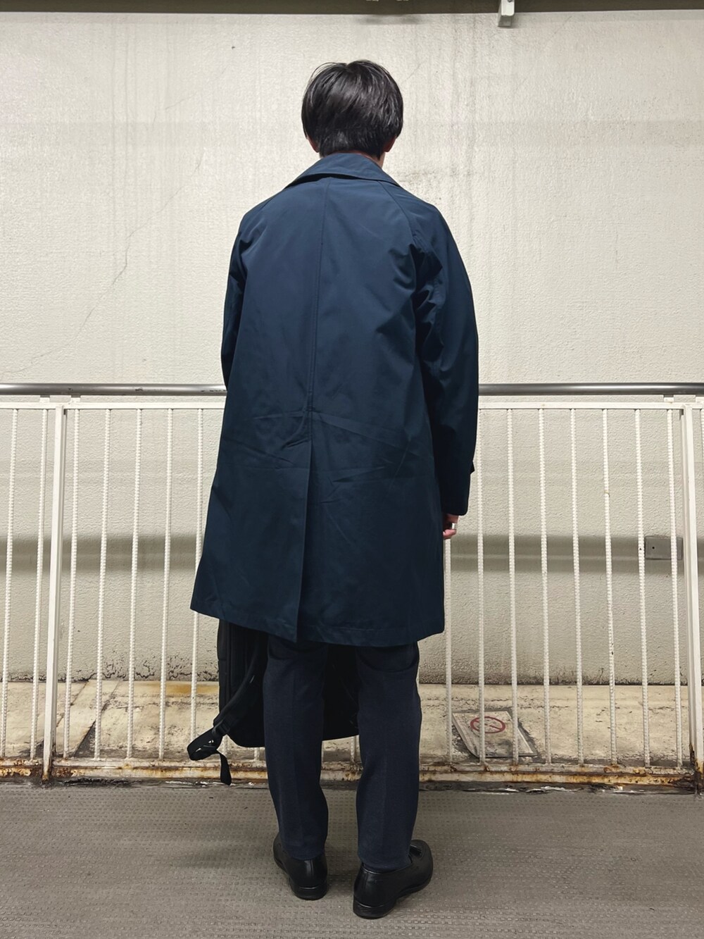 ブラック系のバックパック/リュック、ホワイト系のTシャツ/カットソー、ブルー系のステンカラーコートを着用したメンズの秋コーディネートの6枚目の写真