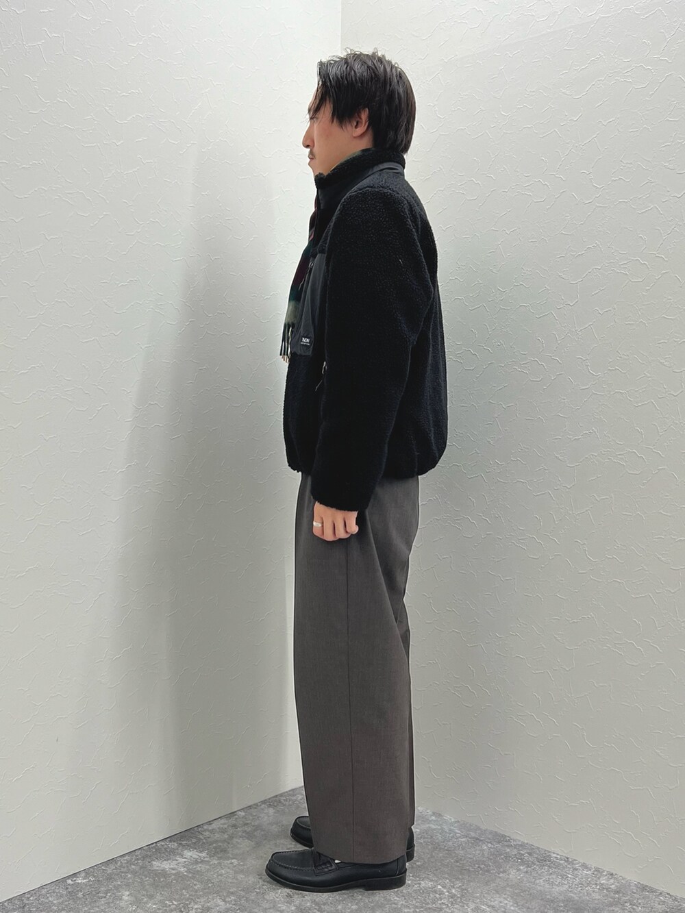 ブラック系のブルゾン、ベージュ系のニット/セーター、グレー系のマフラーを着用したメンズの秋コーディネートの5枚目の写真