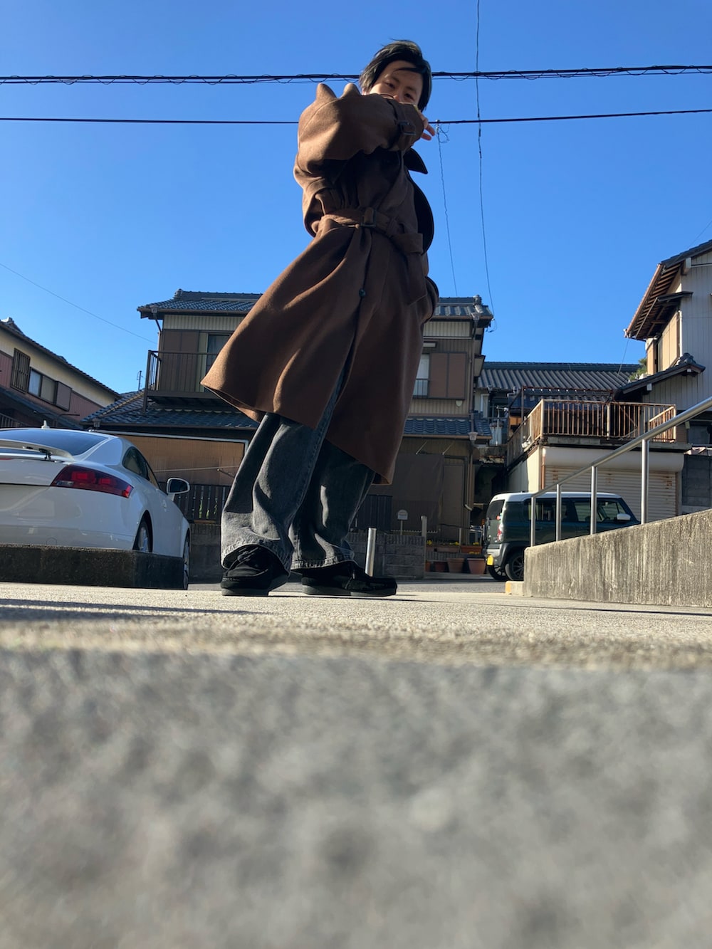 グレー系のデニムパンツ、ブラック系のモカシン/デッキシューズ、ブラウン系のステンカラーコートを着用したメンズの冬コーディネートの2枚目の写真