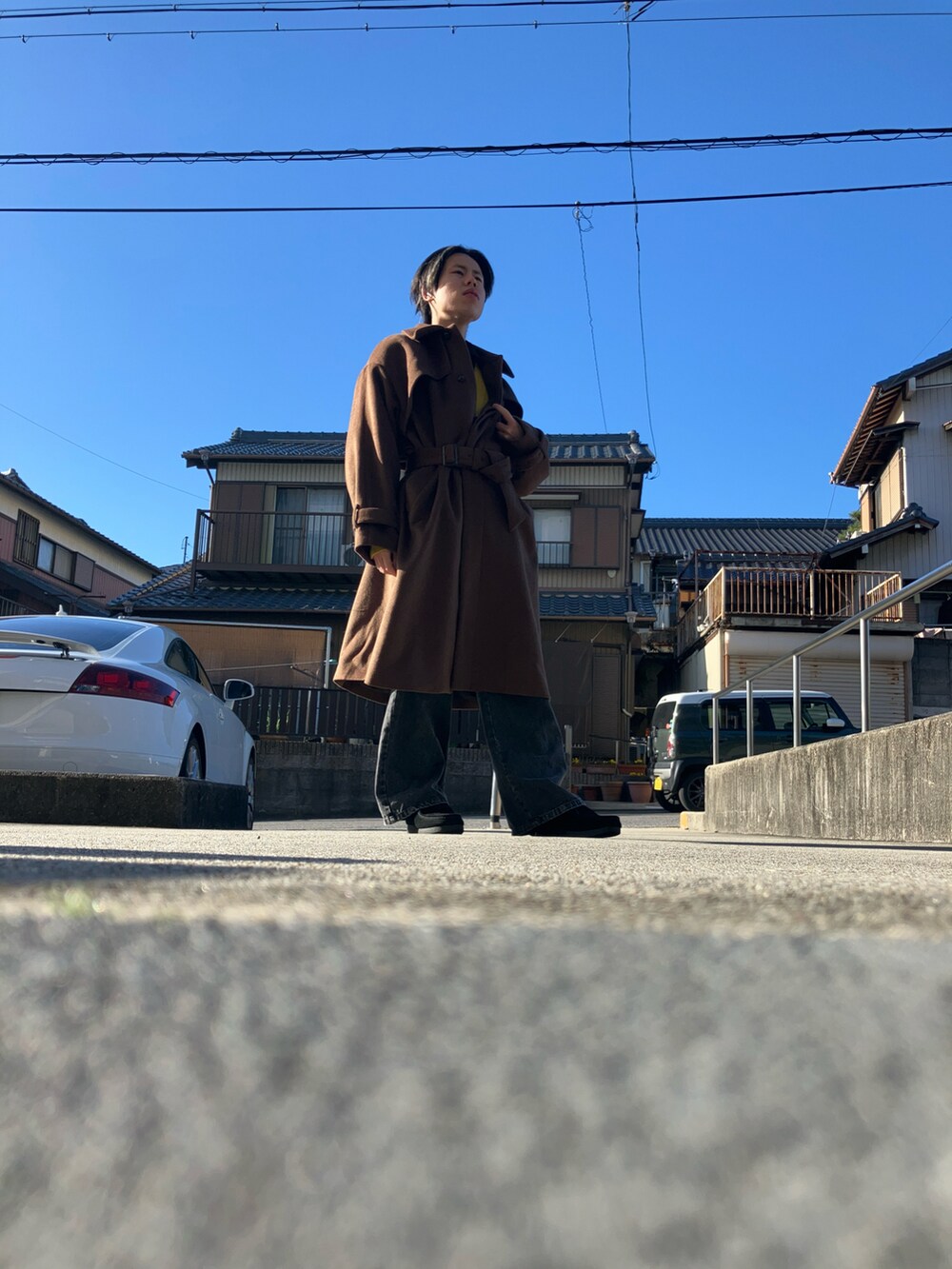 グレー系のデニムパンツ、ブラック系のモカシン/デッキシューズ、ブラウン系のステンカラーコートを着用したメンズの冬コーディネートの3枚目の写真