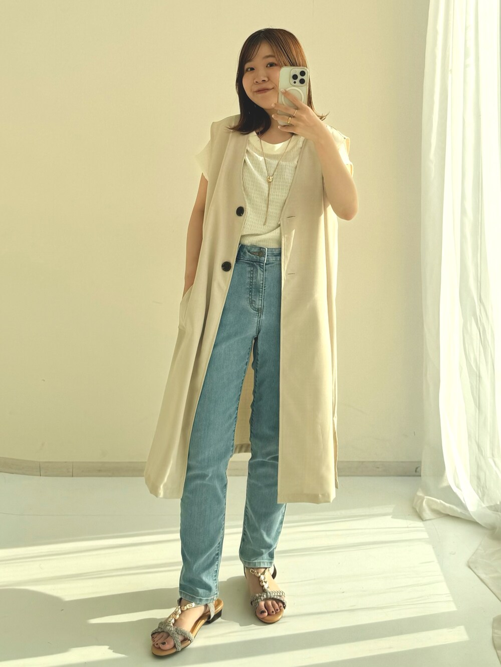 ホワイト系のベスト、ブルー系のパンツ、グリーン系のサンダルを着用したレディースの夏コーディネートの2枚目の写真