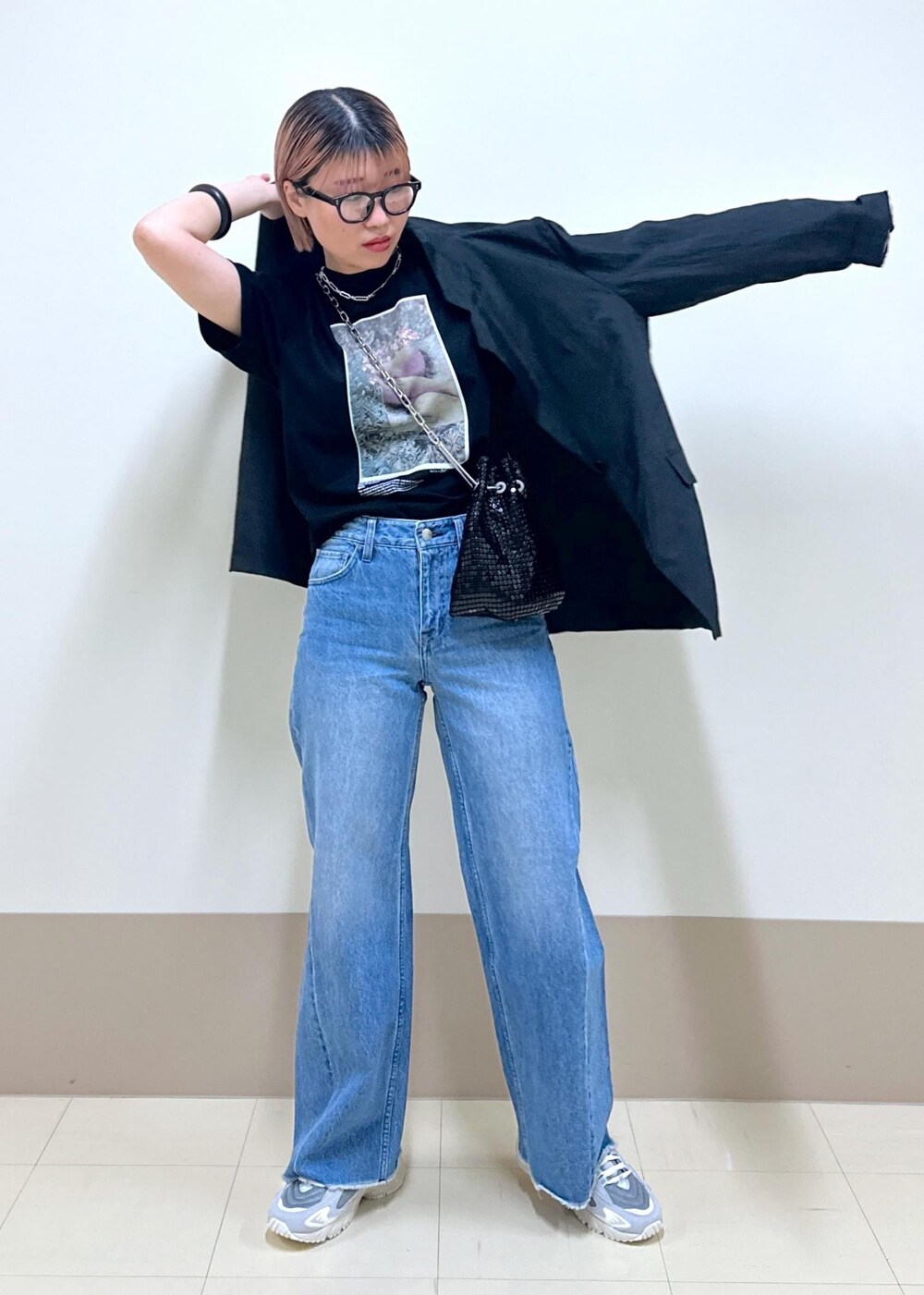 ブルー系のデニムパンツ、ブラック系のテーラードジャケット、ブラック系のハンドバッグを着用したレディースの春コーディネートの7枚目の写真