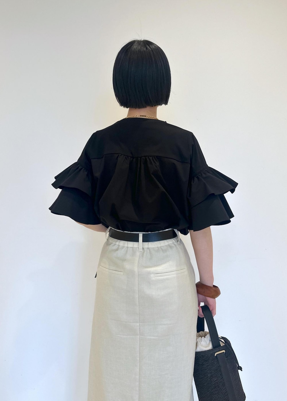 ホワイト系のスカート、ブラック系のサンダル、ブラック系のTシャツ/カットソーを着用したレディースの夏コーディネートの6枚目の写真