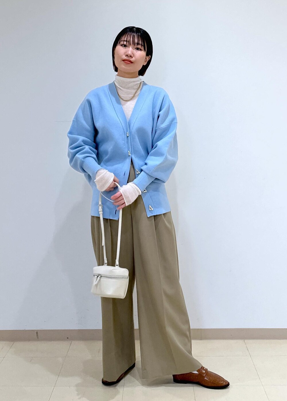 ブラウン系のローファー、ブルー系のカーディガン/ボレロ、ホワイト系のニット/セーターを着用したレディースの冬コーディネートの6枚目の写真