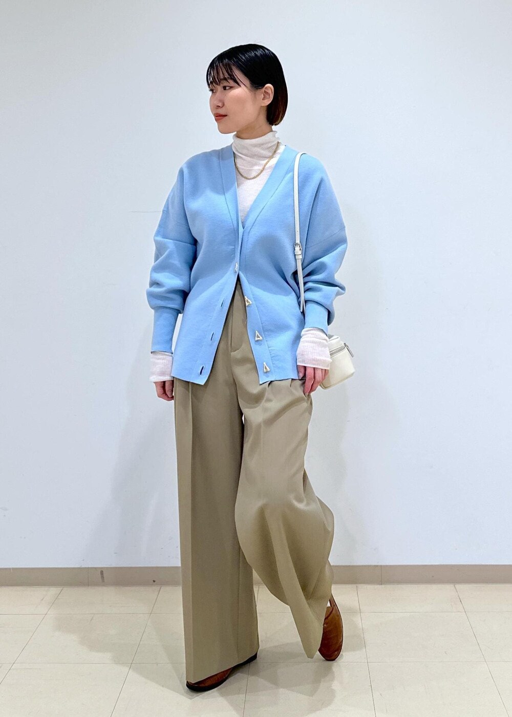 ブラウン系のローファー、ブルー系のカーディガン/ボレロ、ホワイト系のニット/セーターを着用したレディースの冬コーディネートの2枚目の写真