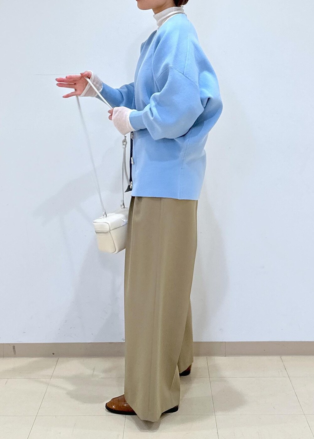 ブラウン系のローファー、ブルー系のカーディガン/ボレロ、ホワイト系のニット/セーターを着用したレディースの冬コーディネートの5枚目の写真