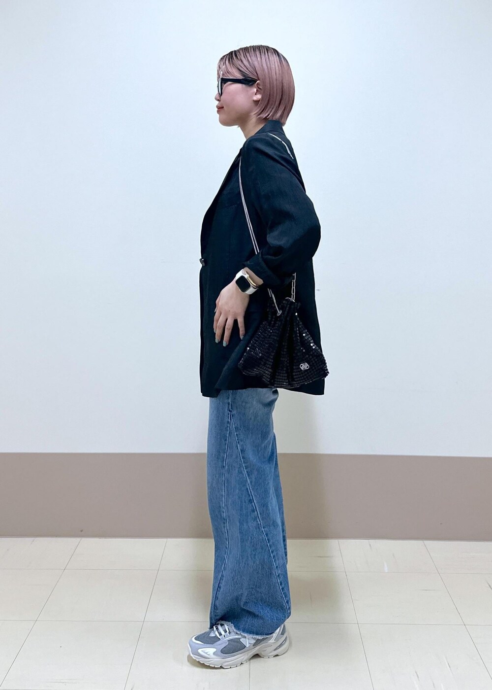 ブルー系のデニムパンツ、ブラック系のテーラードジャケット、ブラック系のハンドバッグを着用したレディースの春コーディネートの3枚目の写真