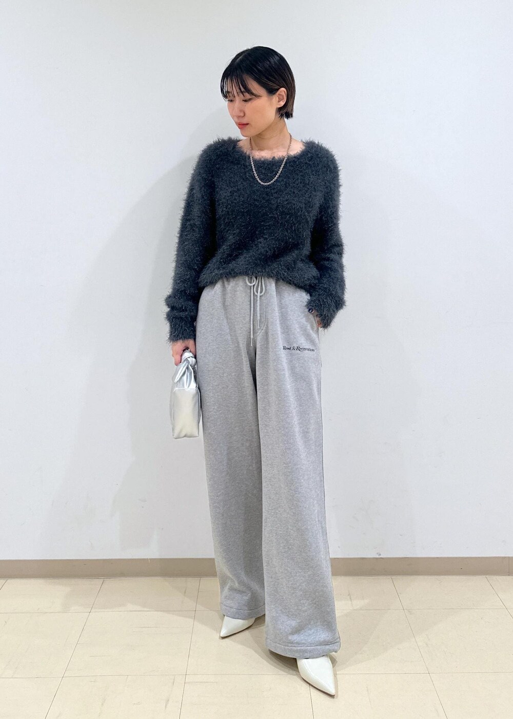 ホワイト系のパンプス、グレー系のニット/セーター、シルバー系のショルダーバッグを着用したレディースの秋コーディネートの5枚目の写真