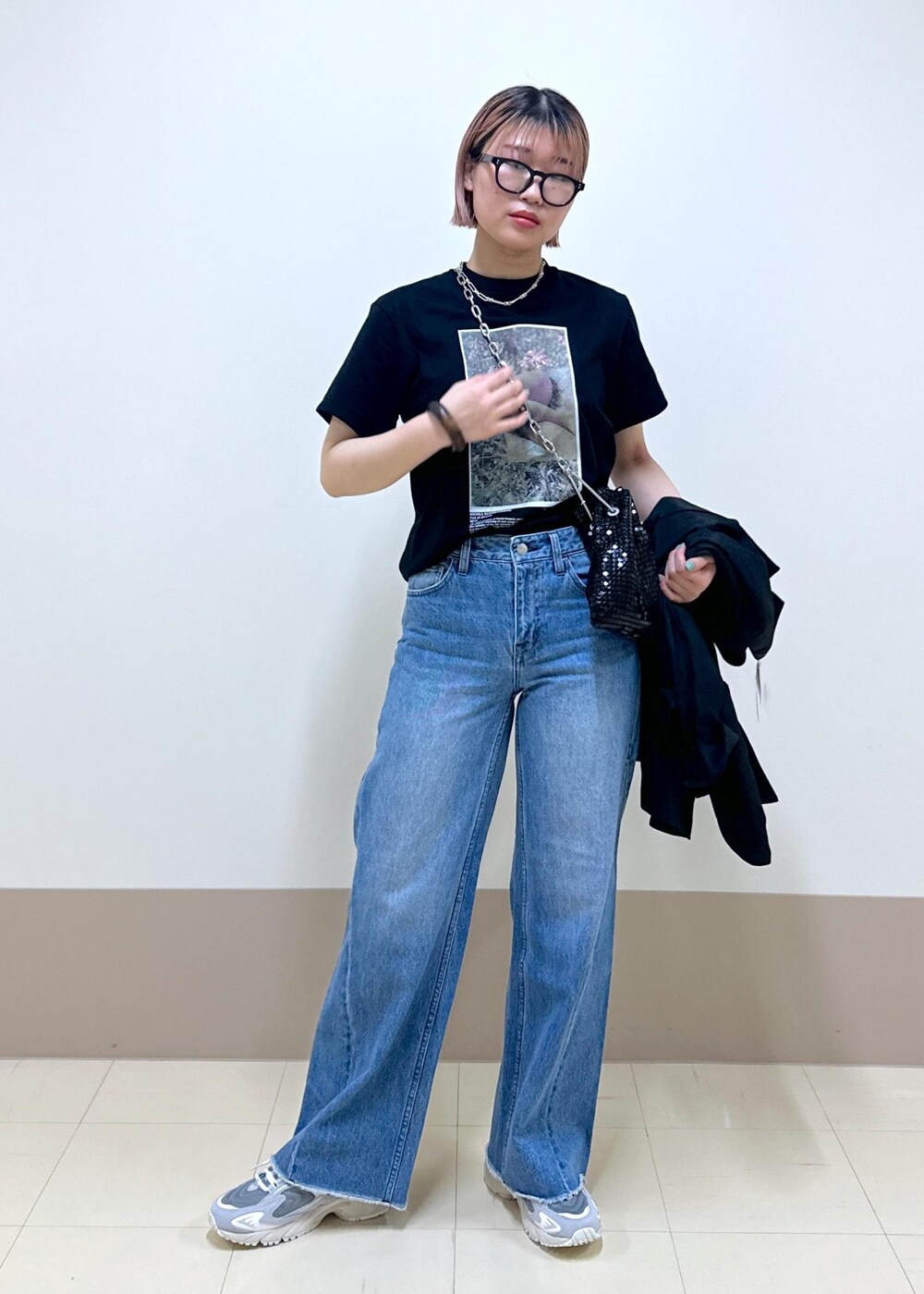 ブルー系のデニムパンツ、ブラック系のテーラードジャケット、ブラック系のハンドバッグを着用したレディースの春コーディネートの5枚目の写真