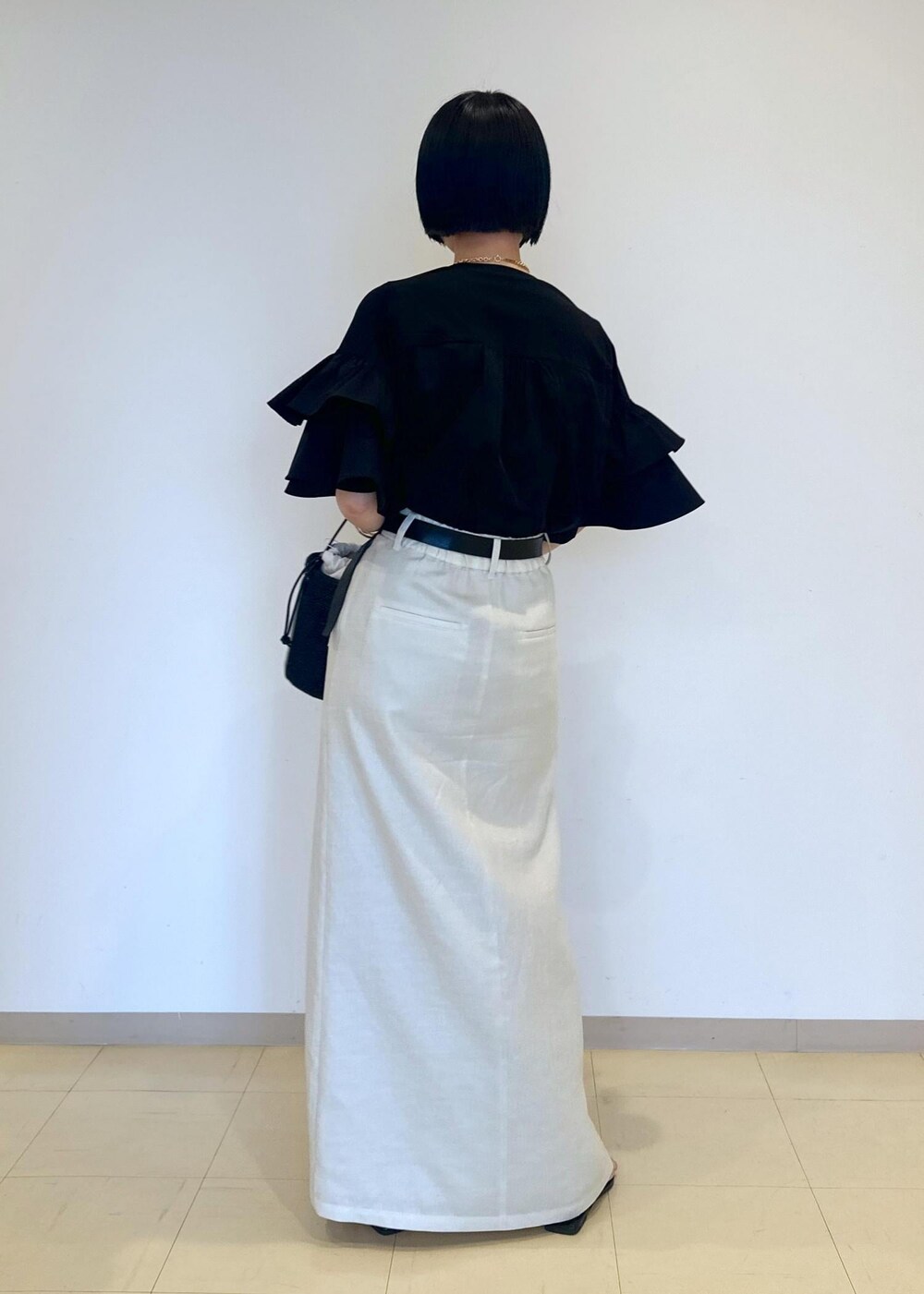 ホワイト系のスカート、ブラック系のサンダル、ブラック系のTシャツ/カットソーを着用したレディースの夏コーディネートの3枚目の写真