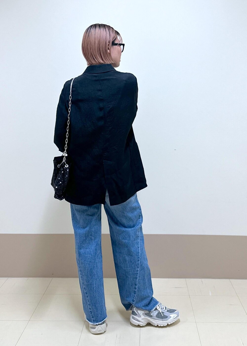 ブルー系のデニムパンツ、ブラック系のテーラードジャケット、ブラック系のハンドバッグを着用したレディースの春コーディネートの4枚目の写真