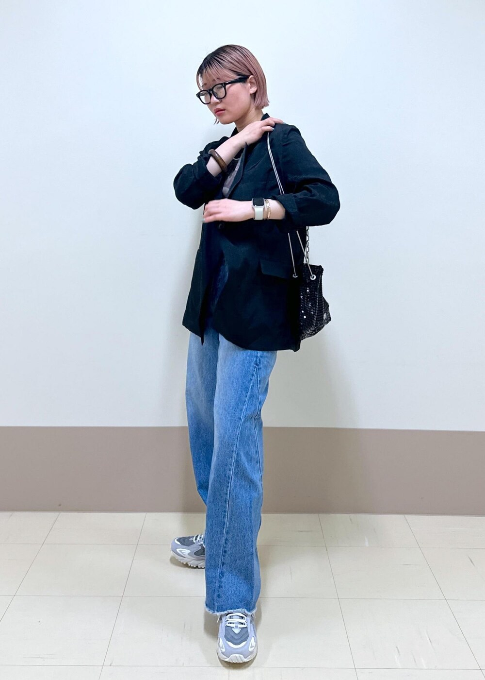 ブルー系のデニムパンツ、ブラック系のテーラードジャケット、ブラック系のハンドバッグを着用したレディースの春コーディネートの2枚目の写真