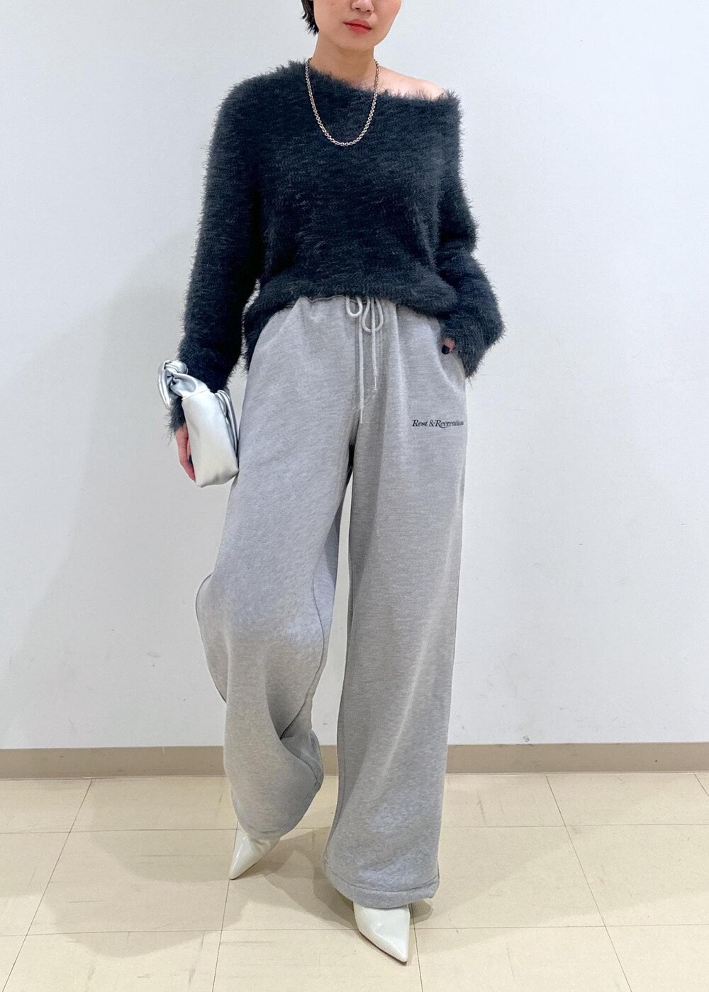 ホワイト系のパンプス、グレー系のニット/セーター、シルバー系のショルダーバッグを着用したレディースの秋コーディネートの2枚目の写真