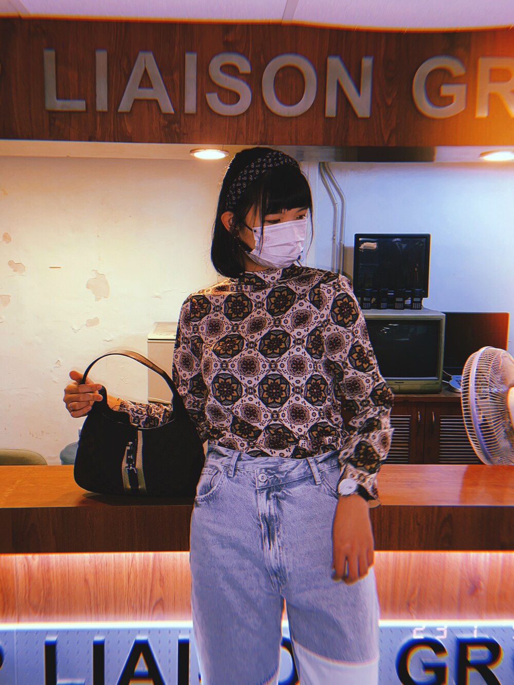 ブルー系のデニムパンツ、ブラウン系のショルダーバッグ、ベージュ系のスニーカーを着用したレディースの春コーディネートの2枚目の写真