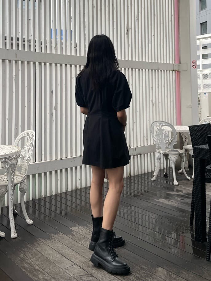 ブラック系のブーツ、ブラック系のワンピース、ホワイト系のショルダーバッグを着用したレディースの春コーディネートの2枚目の写真