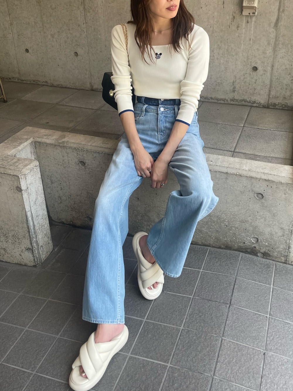 ホワイト系のニット/セーター、ブルー系のデニムパンツ、ブラック系のショルダーバッグを着用したレディースの夏コーディネートの5枚目の写真