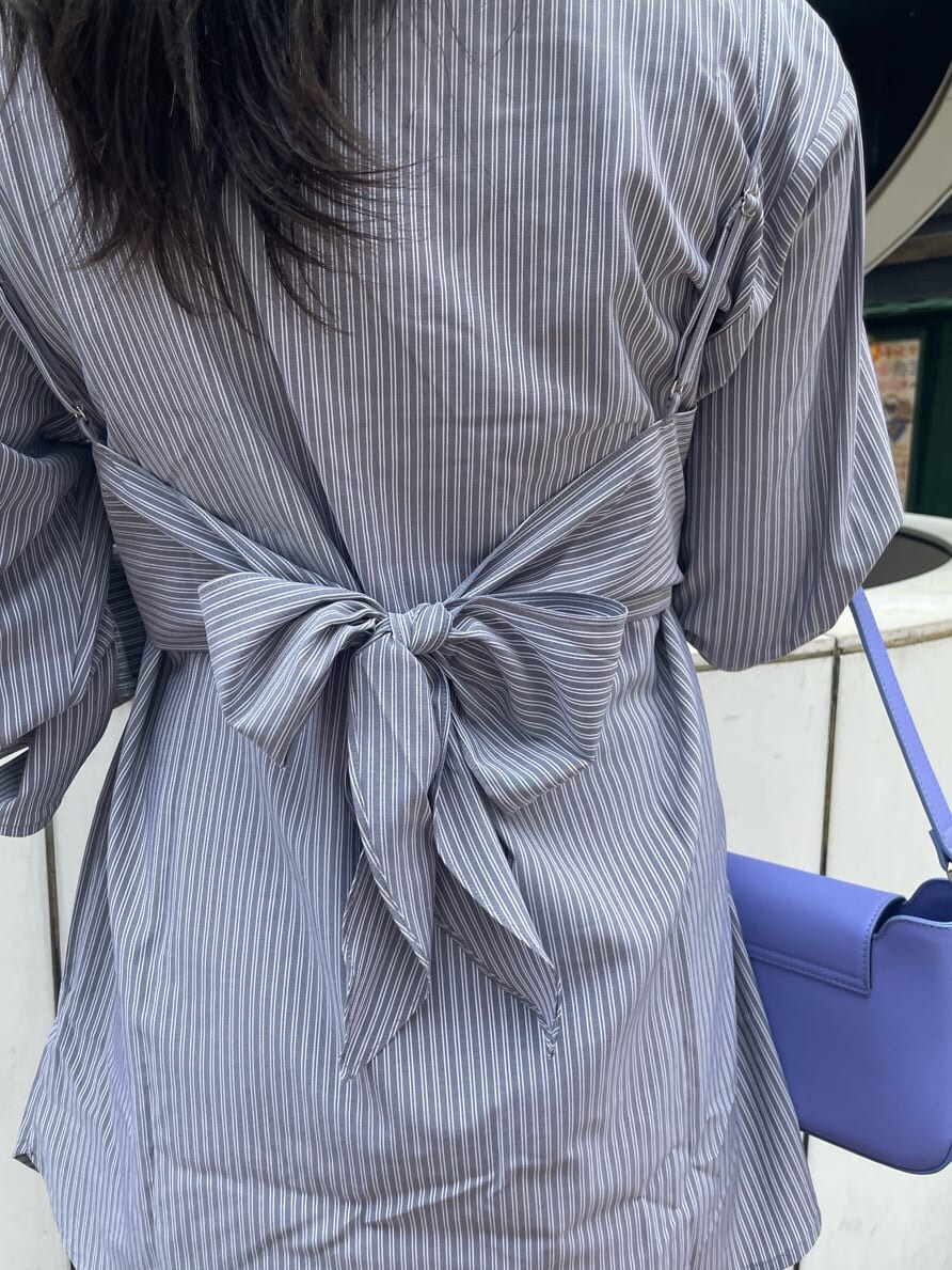 ブラック系のブーツ、ブラック系のワンピース、パープル系のショルダーバッグを着用したレディースの春コーディネートの7枚目の写真