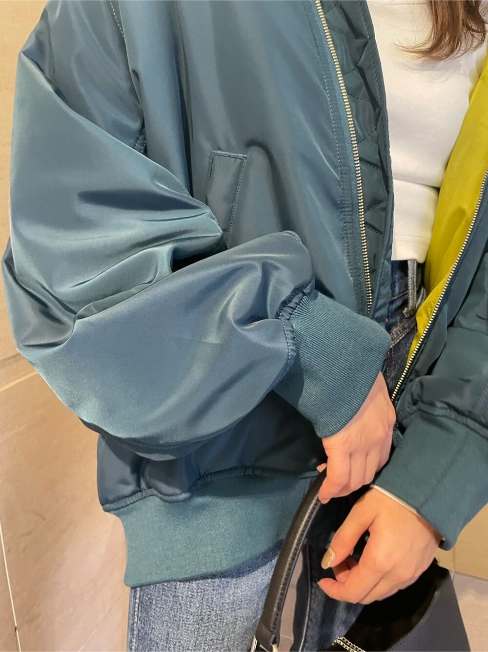 ブルー系のMA-1、ブラック系のブーツ、ブルー系のデニムパンツを着用したレディースの秋コーディネートの9枚目の写真