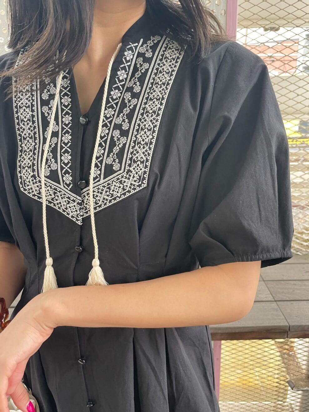 ブラック系のブーツ、ブラック系のワンピース、ホワイト系のショルダーバッグを着用したレディースの春コーディネートの6枚目の写真