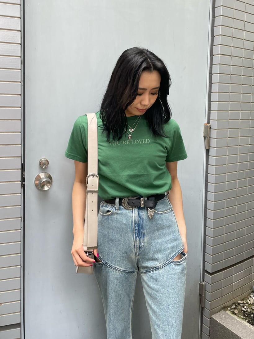 グリーン系のTシャツ/カットソー、ホワイト系のショルダーバッグ、ブルー系のデニムパンツを着用したレディースの春コーディネートの4枚目の写真