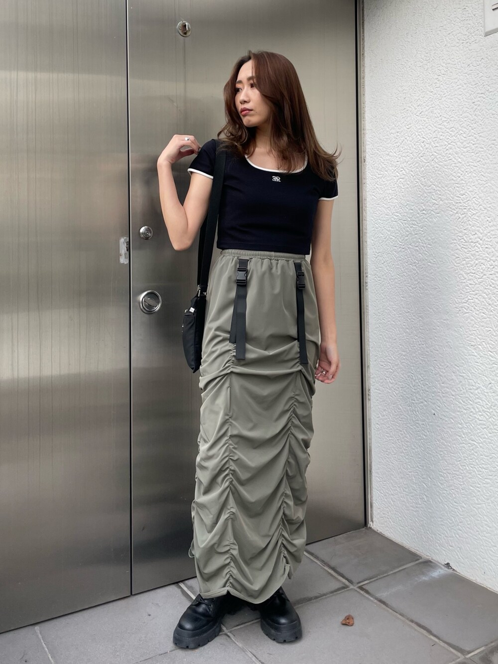 ブラック系のTシャツ/カットソー、グリーン系のスカート、ブラック系のブーツを着用したレディースの春コーディネートの3枚目の写真