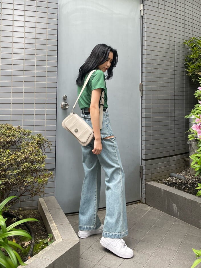 グリーン系のTシャツ/カットソー、ホワイト系のショルダーバッグ、ブルー系のデニムパンツを着用したレディースの春コーディネートの2枚目の写真