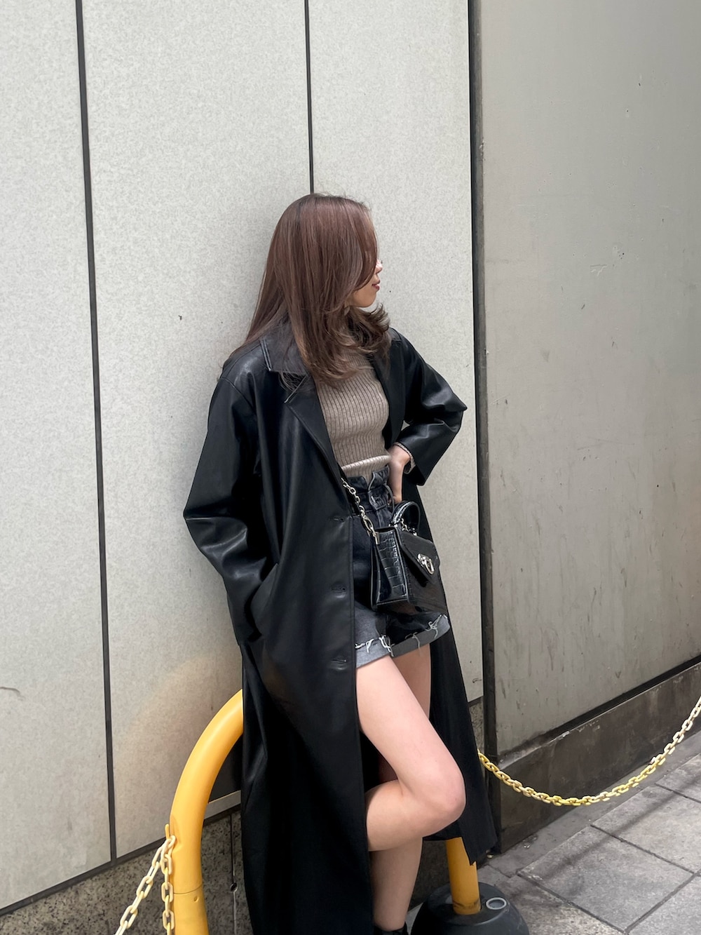 グレー系のニット/セーター、ブラック系のチェスターコート、ブラック系のデニムパンツを着用したレディースの冬コーディネートの3枚目の写真