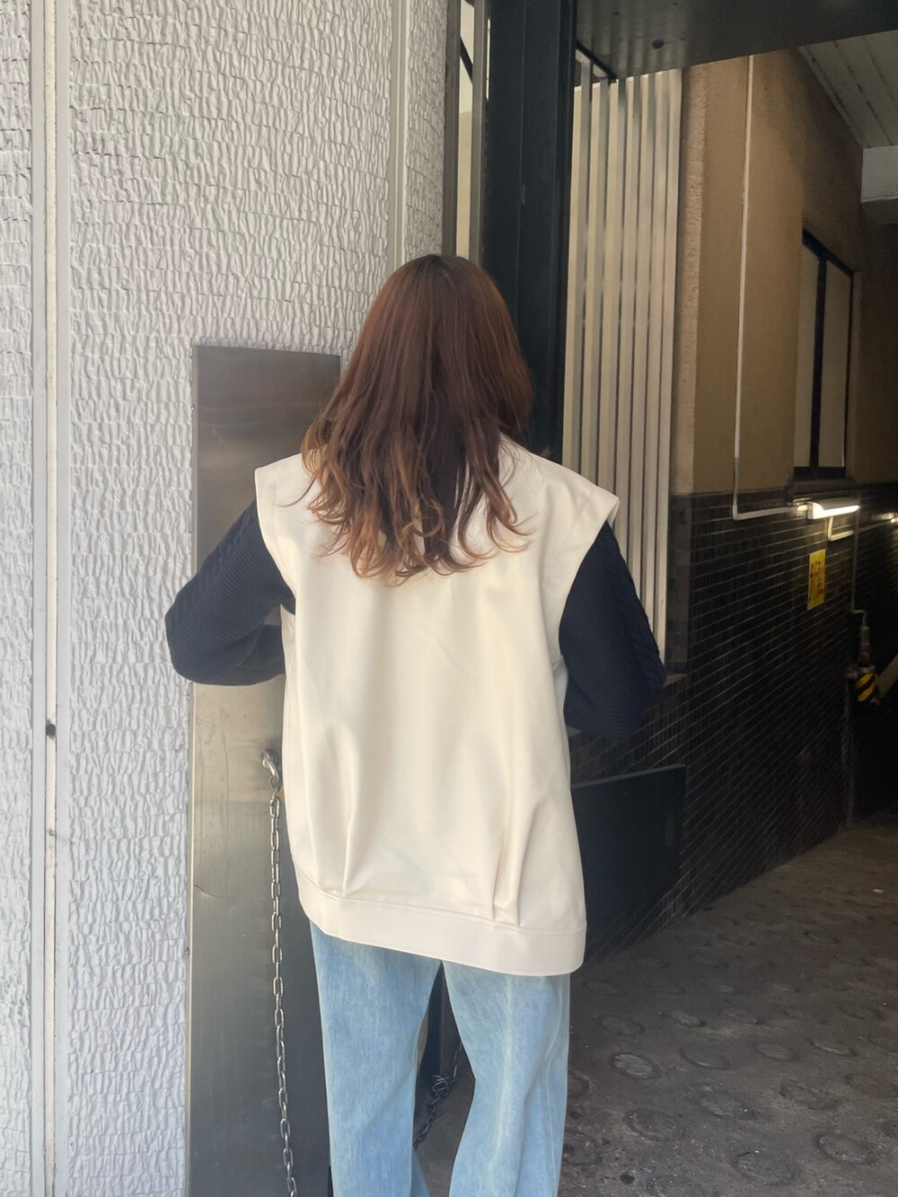 ブルー系のデニムパンツ、ブラック系のニット/セーター、ホワイト系のライダースジャケットを着用したレディースの冬コーディネートの6枚目の写真